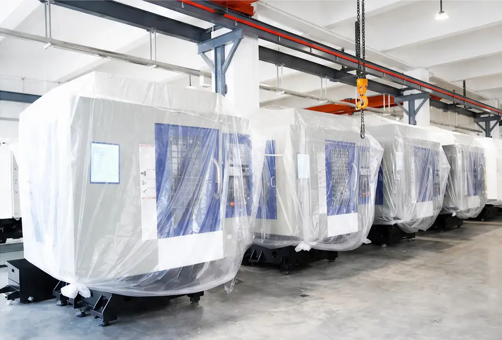 Machines wrapped in protective film under the factory crane, ready for export